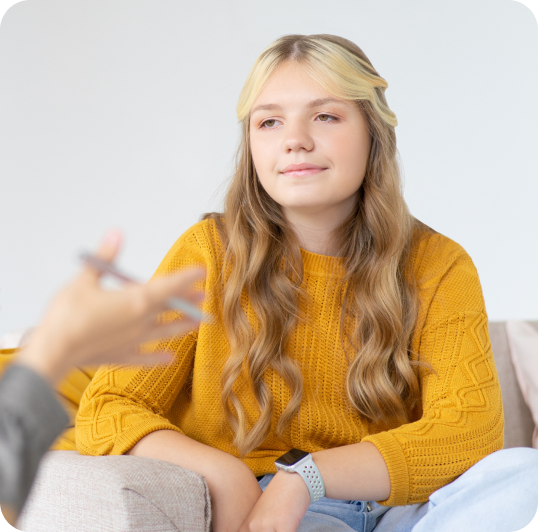 Teen sits on couch and listens to therapist talk