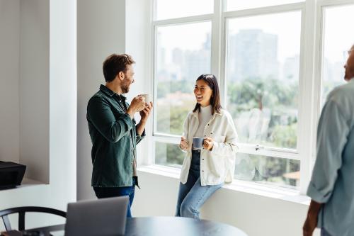 Two people sit coffee and laugh while taking a break from addiction therapy program meeting